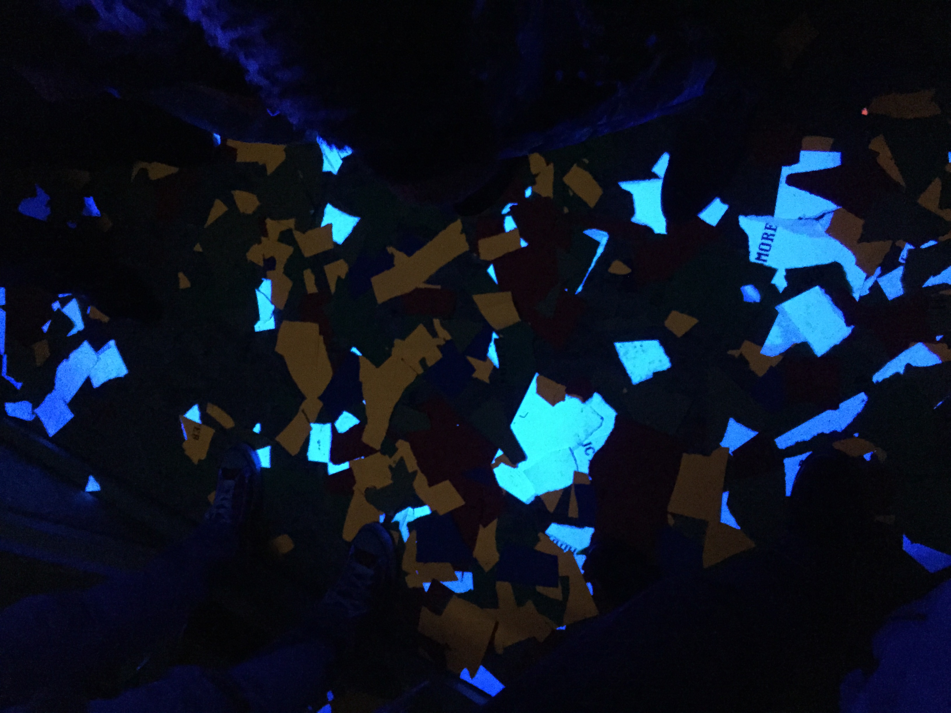 Inside the Cubic Reset cube — confetti and torn papers on the floor under blacklight