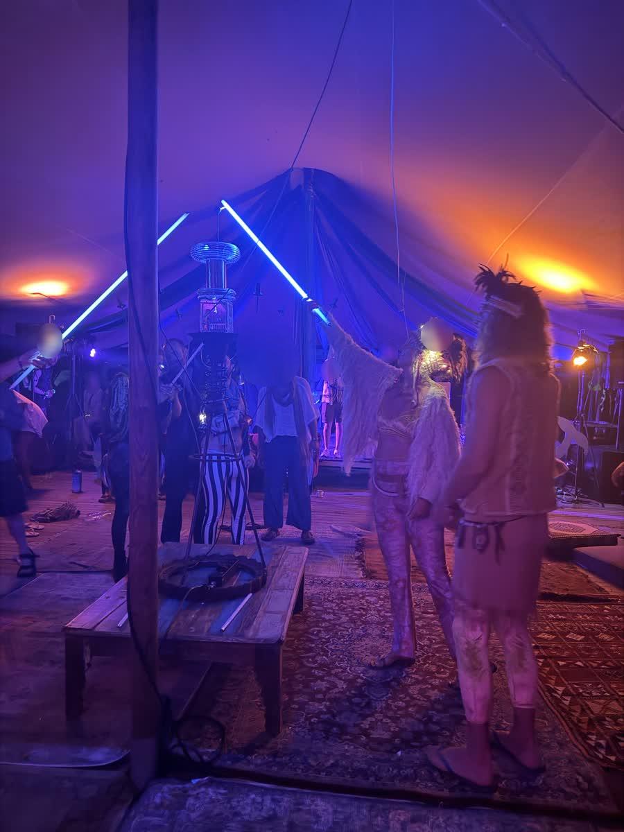 Figures reach glowing tubes toward the top of the coil under blue light