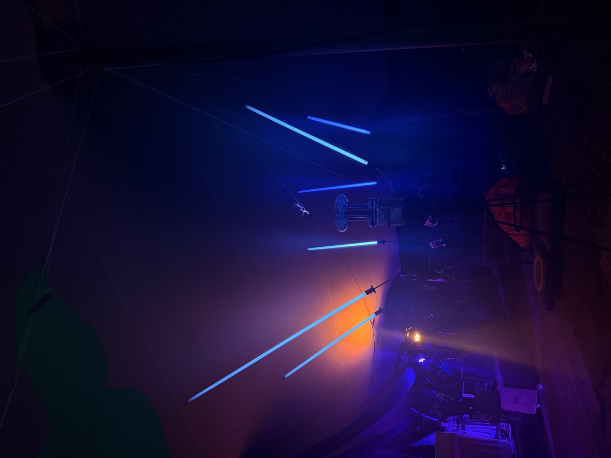 Long-exposure: glowing tubes streak the dark like a field of blue and orange rays around the coil