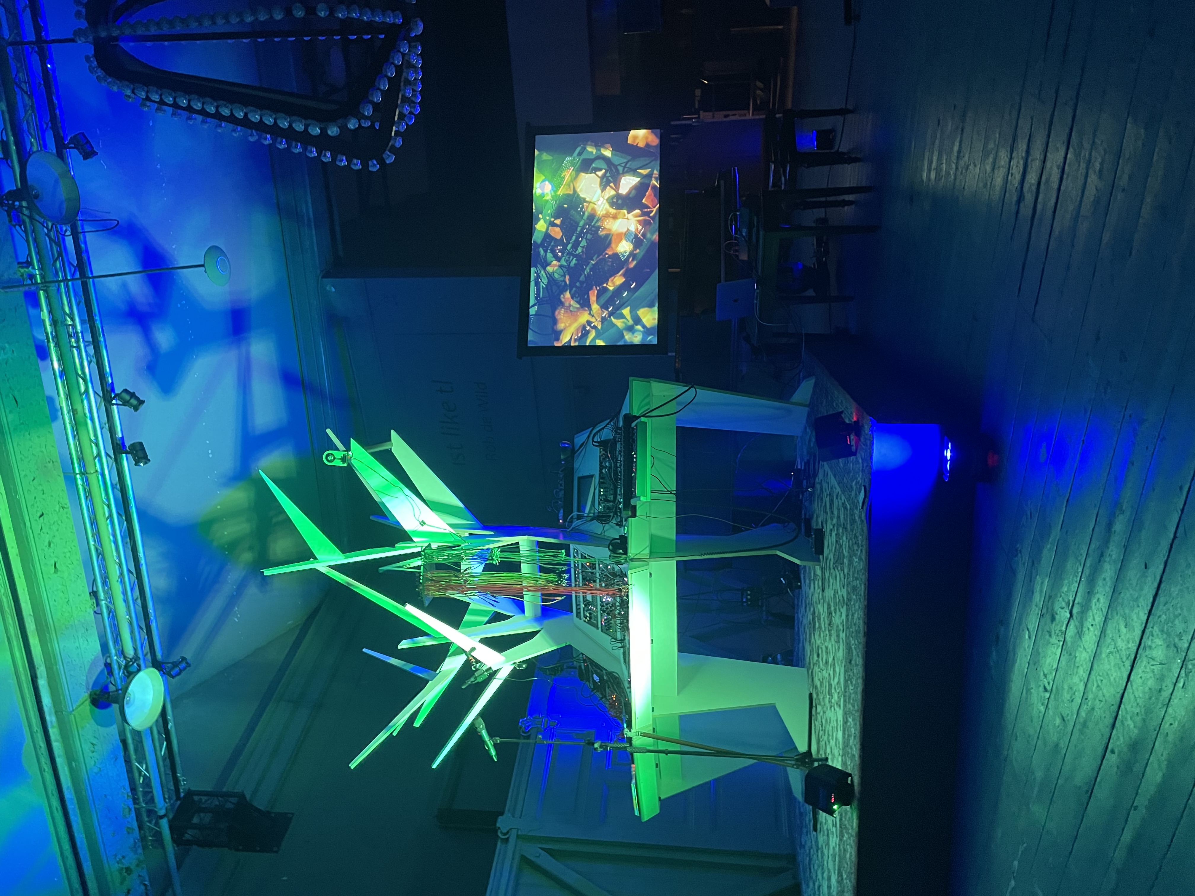 Mayor Manor stage — green and blue lights, white branching sculpture, modular rig, video screen with projection, mirrorball